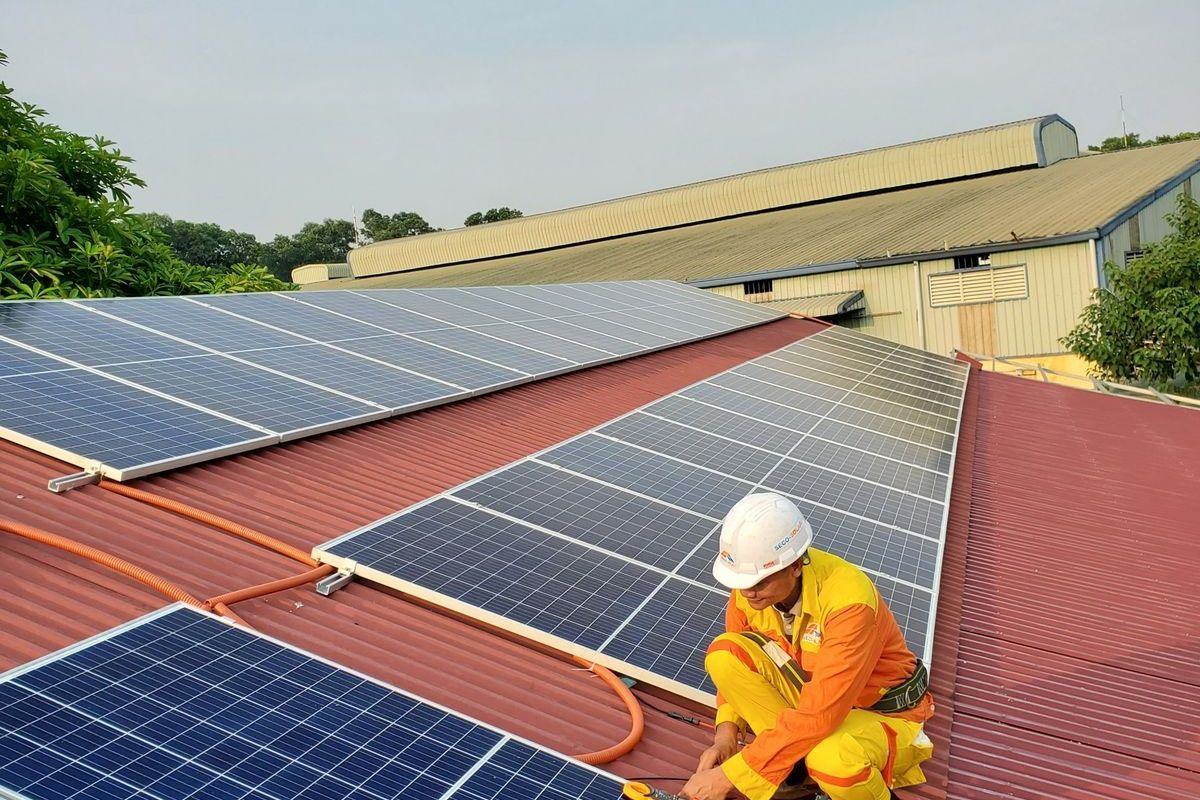 Installer in hi-vis working on a rooftop solar array