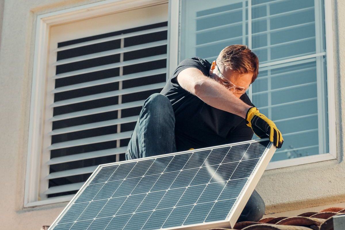Installer fitting a solar panel on a tiled roof