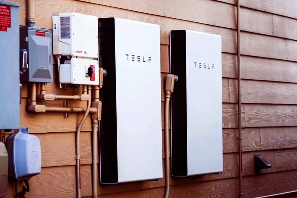 Two wall-mounted home batteries installed on the outside wall of a house