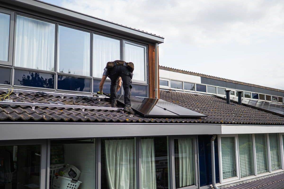 Installer working on solar panels on a house roof