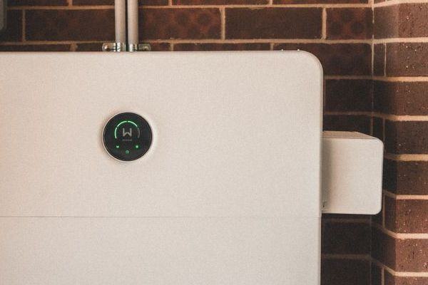 Wall-mounted home battery on a brick wall